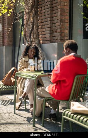 Fashionable african american man and woman friends spending day break in street cafe Stock Photo