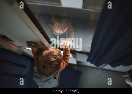 High angle view of curious boy leaning on train window Stock Photo