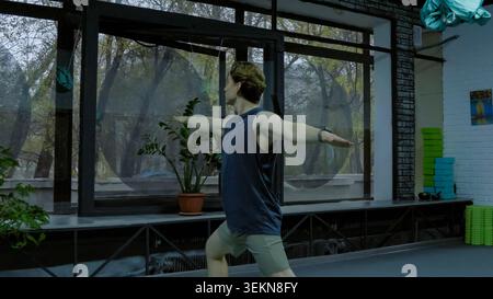 Wellness lifestyle concept featuring active man practicing standing warrior y Stock Photo