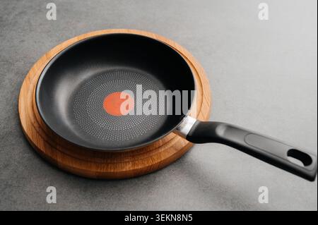 Empty non-stick frying pan on a wooden board Stock Photo