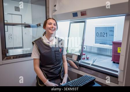 Smiling female scientist sitting next to laminar cabinet in laboratory Stock Photo