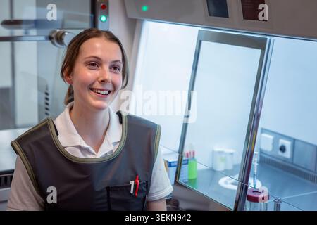 Smiling female scientist looking away while sitting in research laboratory Stock Photo