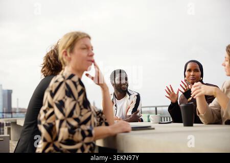 Group of diverse professionals discussing strategies while sitting on office terrace Stock Photo