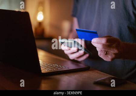 Midsection of man doing online payment through smart phone and credit card at home Stock Photo