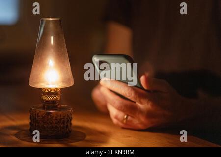 Midsection of man using smart phone next to illuminated lantern Stock Photo