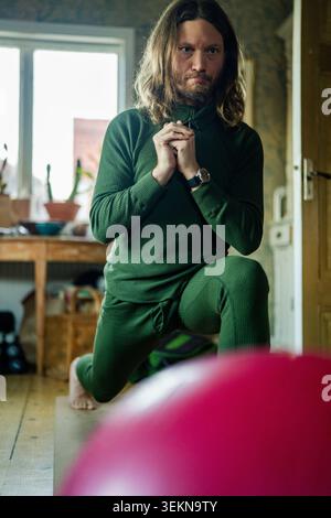 Concentrated man doing deep lunge on yoga mat while exercising at home Stock Photo