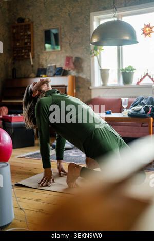 Active man doing camel pose on yoga mat at home Stock Photo