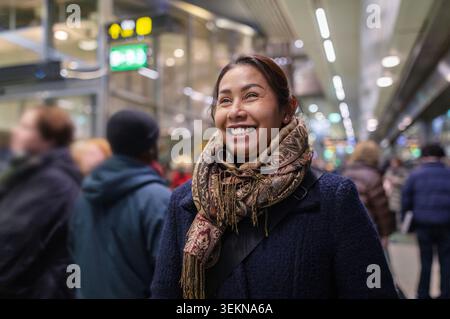 Happy woman in warm clothes at railway station Stock Photo