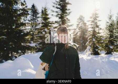 Thoughtful woman touching temple while standing in winter forest Stock Photo