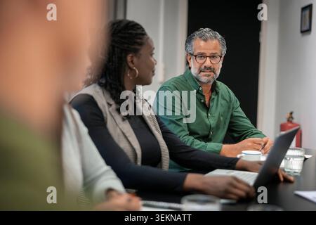 Mature male entrepreneur talking with colleagues during meeting in office conference room Stock Photo