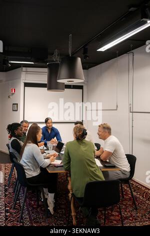 Group of business professionals discussing ideas with each other in office meeting Stock Photo