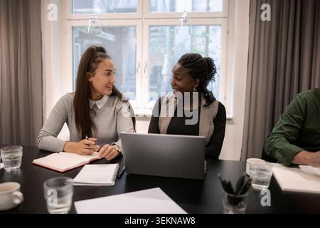 Multiracial female business coworkers talking with each other in meeting at office Stock Photo
