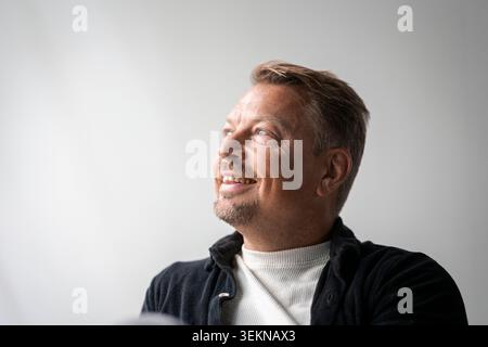 Smiling mature businessman looking away against wall Stock Photo