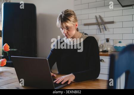Focused female freelancer using laptop while working at home Stock Photo