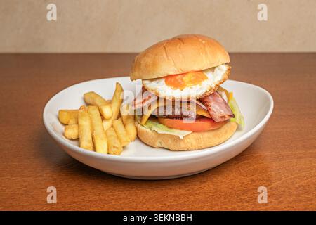 A dry-aged beef burger with an umami touch of soy and ginger sauce, topped with fresh radish sprouts and avocado slices fanned out on a golden brioche Stock Photo