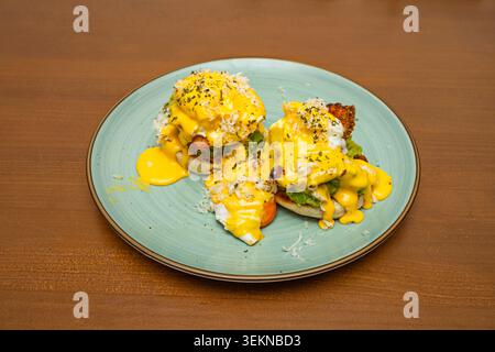 Florentine Eggs Benedict on a bed of sautéed spinach peeking out from under the egg, with a lemon hollandaise and citrus zest, served on a black slate Stock Photo