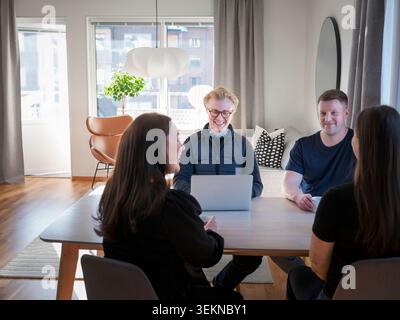 Smiling male agent using laptop while sitting with family at table in home Stock Photo