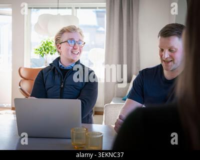 Smiling male architect wearing eyeglasses talking with man at home Stock Photo