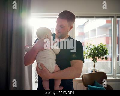 Affectionate father embracing male toddler at home Stock Photo