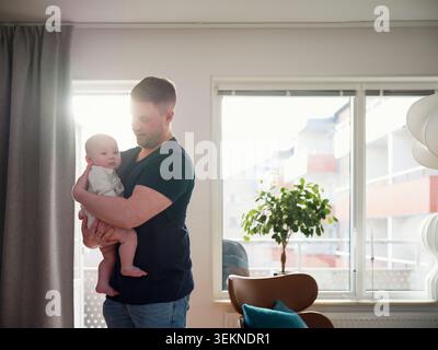 Father embracing baby son while spending leisure time at home Stock Photo