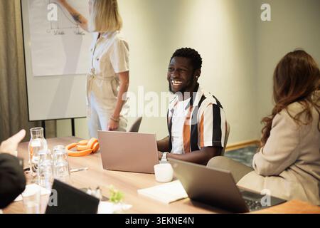 Happy male employee laughing while sitting with colleagues in office meeting Stock Photo