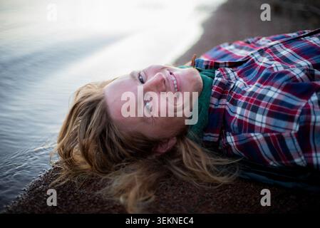 Portrait of smiling man lying down by shore at beach Stock Photo