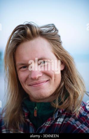 Portrait of smiling man with long blond hair Stock Photo