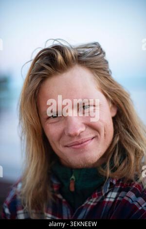 Smiling man with long blond hair Stock Photo