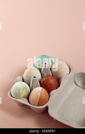 Colorful Easter eggs in egg box on beige surface Stock Photo