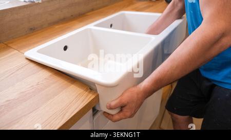 Precise And Efficient Sink Fixing Techniques Demonstrated. Demonstrating Skilled Craftsmanship In Setting Ceramic Sinks Into Surfaces Stock Photo