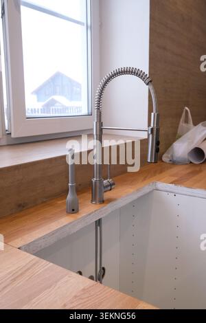 A man installs a sink in the kitchen. Assembly of kitchen furniture. Stock Photo