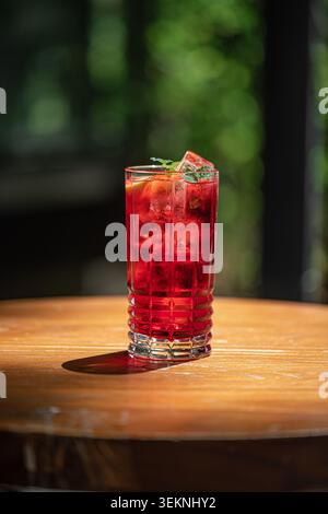 Vibrant red cocktail with ice on table Stock Photo