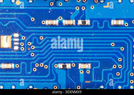Blue circuit board surface featuring electronic pathways and tiny components Stock Photo