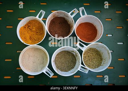 Various spices arranged in plastic cups, such as turmeric, pepper, salt, allspice, paprika and herbs for outdoor cooking at a large party, top view from above, selected focus Stock Photo