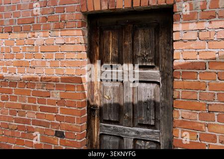 Old weathered wooden door in a red brick wall. Stock Photo