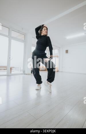 Solo contemporary dancer practicing expressive moves in a bright minimalist dance studio space Stock Photo