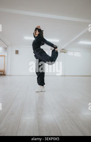 Female dancer stretching in a bright studio practicing a balancing contemporary dance pose Stock Photo