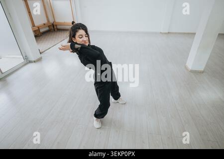 Solo female dancer practicing contemporary movement in a bright empty dance studio during rehearsal Stock Photo
