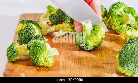 Broccoli florets being chopped and separated on the cutting board. Stock Photo