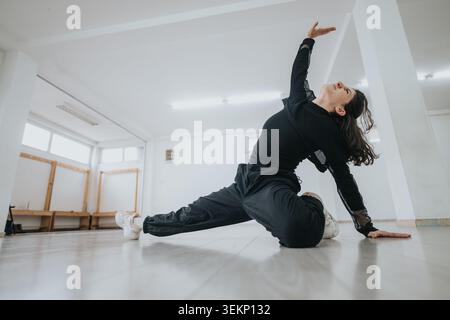Female contemporary dancer stretching on the studio floor in a modern expressive pose Stock Photo