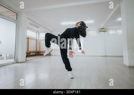 Solo dancer in a bright studio performing a contemporary movement with expressive balance and motion Stock Photo
