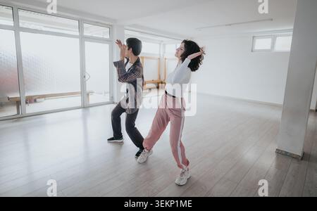 Two young dancers practicing contemporary movement in a bright empty studio during rehearsal Stock Photo