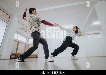Two dancers practicing a contemporary partner routine in a bright empty studio space Stock Photo