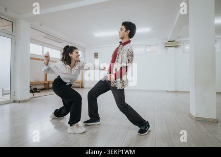 Two dancers practicing playful partner moves in a bright empty dance studio during rehearsal Stock Photo