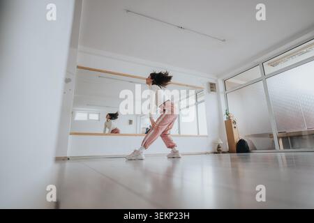 Young dancer practicing energetic choreography in a bright modern dance studio with mirror Stock Photo