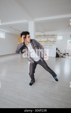 Male dancer practicing expressive movement in a bright studio with trophies on display Stock Photo