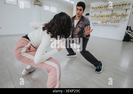 Two dancers practicing contemporary partner moves in a bright studio with trophy display Stock Photo