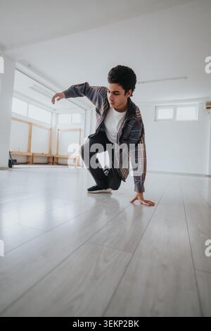 Young male dancer practicing a break dance move alone in a bright empty dance studio space Stock Photo