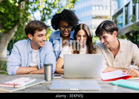 Diverse MBA students studying together with laptop in campus setting Stock Photo