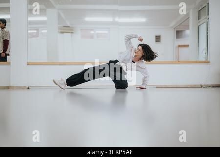 Young female dancer practicing floor moves in a bright studio during a street dance rehearsal Stock Photo